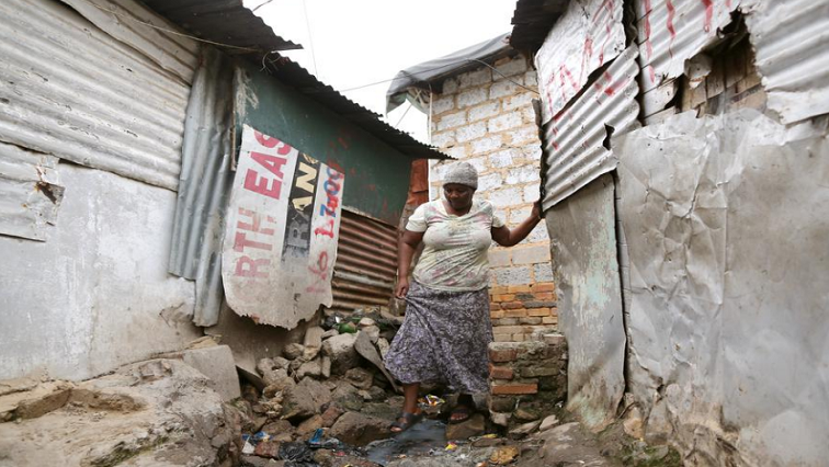 A resident walks between shacks next to her home.