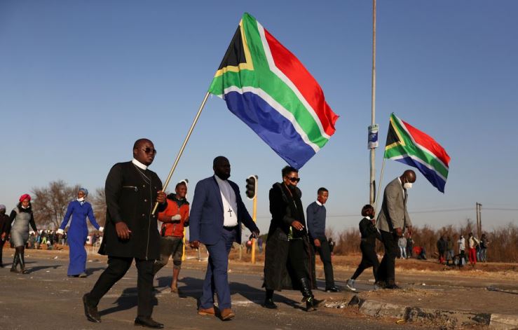 Religious leaders carrying South African flags walk near a looted shopping mall as the country deployed the army to quell unrest linked to the jailing of former South African President Jacob Zuma, in Vosloorus, South Africa, July 14, 2021.