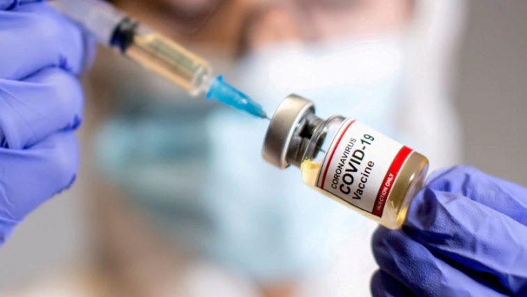 A woman holds a small bottle labelled with a "Coronavirus COVID-19 Vaccine" sticker and a medical syringe in this illustration taken October 30, 2020.