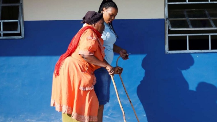 An Electoral Commission of South Africa (IEC) offical assits a blind voter to cast her ballot at a polling station, during the South Africa's parliamentary and provincial elections, in Nkandla,