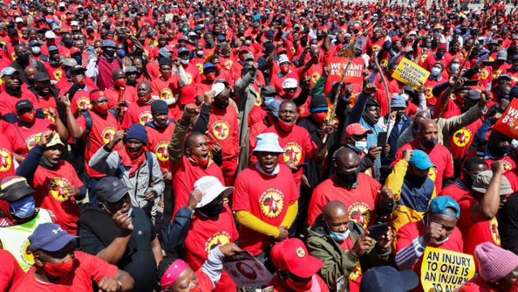 File Image | Members of the National Union of Metalworkers of South Africa hold placards as they gather ahead of an indefinite strike, threatening to choke supplies of parts to make new cars and accessories, in Johannesburg, South Africa, October 5, 2021.