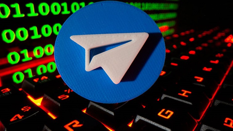 A 3D printed Telegram logo is pictured on a keyboard in front of binary code in this illustration.