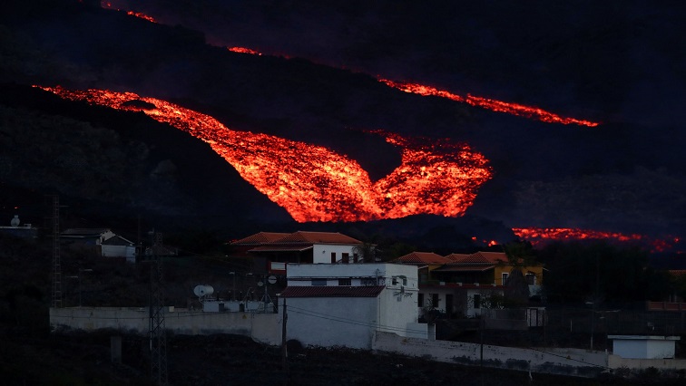 Lava flows down behind houses in Los Llanos as the Cumbre Vieja volcano continues to erupt on the Canary Island of La Palma, as seen from Tajuya, Spain,
