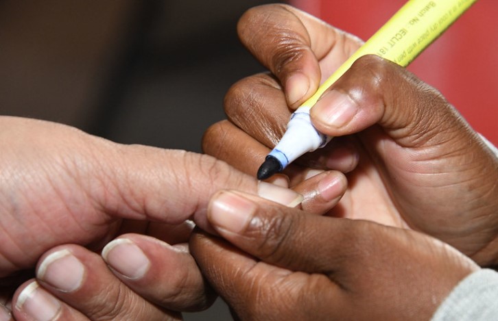 An IEC official putting ink on  a voters finger.