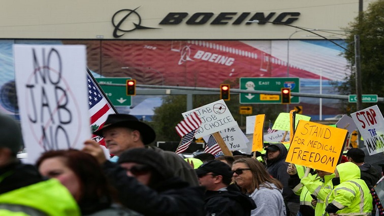 Boeing employees and others line the street to wave signs and American flags to protest the company's COVID-19) vaccine mandate, outside the Boeing facility in Everett, Washington.
