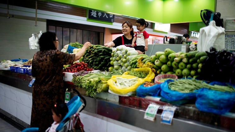 Two grandmothers with their granddaughter trade vegetables at a market on the outskirts of Shanghai, China June 3, 2021. REUTERS/Aly Song/File Photo