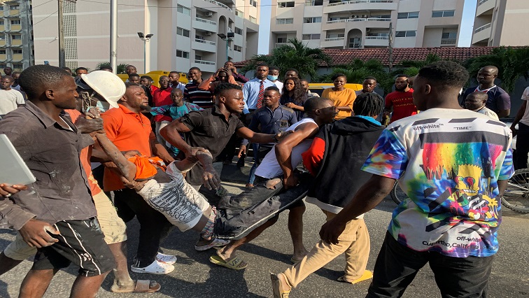 Men carry a man who was rescued at the site of a collapsed 21-story building in Ikoyi, Lagos, Nigeria, November 1, 2021.
