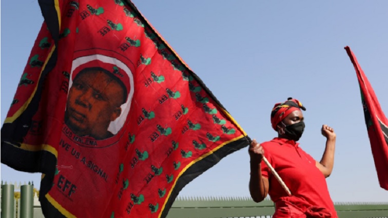 A woman holding an EFF flag with bearing the face of the party leader Julius Malema.