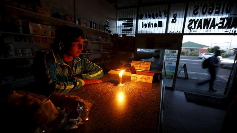 [File Image] A shopkeeper waits for customers in his candlelit fast food store during a load shedding electricity blackout in Cape Town.