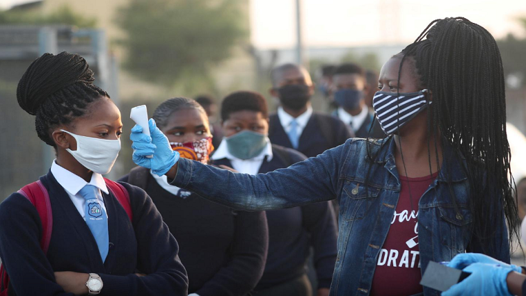 A teacher screens students as schools begin to reopen in Langa in the Western Cape on June 8, 2020.