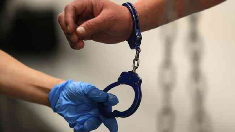 An offical with gloves places handcuffs during an arrest.
