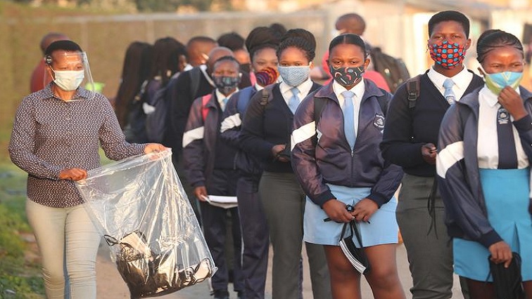 A teacher distributes masks to students as schools begin to reopen after the coronavirus disease (COVID-19) lockdown in Langa township in Cape Town, South Africa June 8, 2020.
