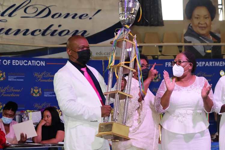 MEC Tate Makgoe with his trademark white suit holding the trophy for the province's top matriculant