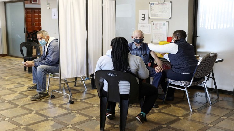 A man is vaccinated as another looks on while waiting to receive a dose of a coronavirus disease (COVID-19) vaccine in Meyerton, south of Johannesburg, South Africa June 23, 2021.