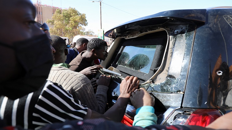 People look into an armoured car riddled with bullets as they gather, after Burkina Faso President Roch Kabore was detained at a military camp following heavy gunfire near the president's residence, in Ouagadougou, Burkina Faso