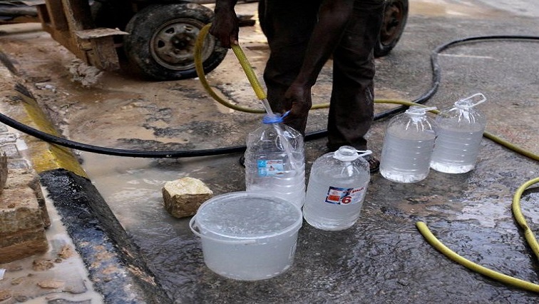 A man is pictured refilling his water bottles from a water tanker.