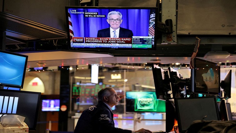 Federal Reserve Chair Jerome Powell is seen delivering remarks on a screen as a trader works on the trading floor at the New York Stock Exchange (NYSE) in Manhattan, New York City, U.S., December 15, 2021.
