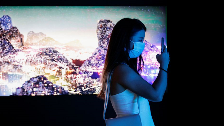 A visitor takes a photo in front of a video installation "Glows in the Night" by Chinese contemporary artist Yang Yongliang, which will be converted into NFTs and auctioned online at Sotheby's, at the Digital Art Fair, in Hong Kong.