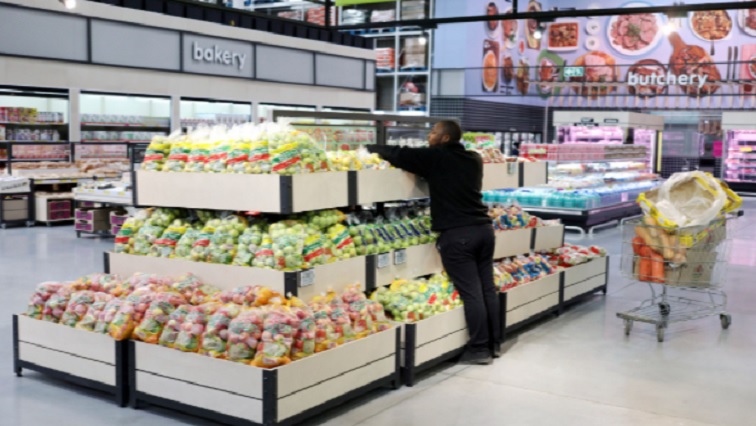 A worker arranges fruits on a shelf.