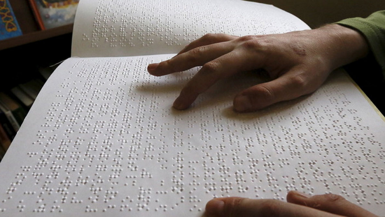 A visually impaired girl reads a Braille.