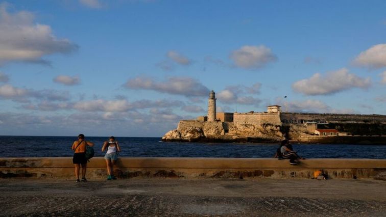 A tourist puts on a face mask after posing for a picture at the seafront El Malecon in Havana, Cuba, February 7, 2022.