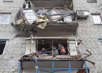 People remove debris from an apartment building, which locals said was damaged by recent shelling, in the separatist-controlled town of Yasynuvata (Yasinovataya) in the Donetsk region, Ukraine March 2, 2022.