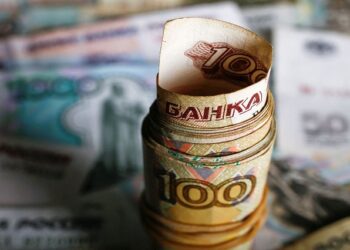 A picture illustration shows rolled Russian rouble banknotes on a table.
