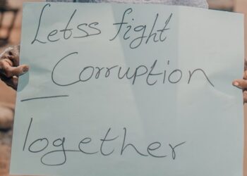 A woman holds a poster with the words, "Lets fight corruption together."