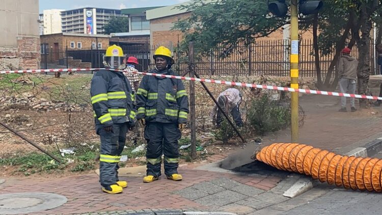 Johannesburg emergency services firefighters standing next to a manhole.