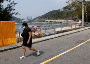 A woman walks past fences placed to block access to Deep Water Bay beach during the coronavirus disease (COVID-19) pandemic, in Hong Kong, China
