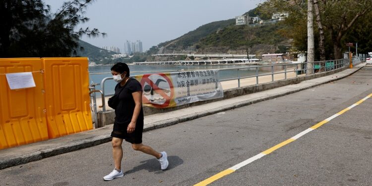 A woman walks past fences placed to block access to Deep Water Bay beach during the coronavirus disease (COVID-19) pandemic, in Hong Kong, China