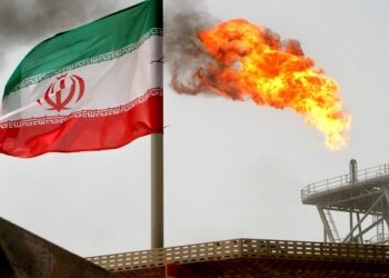 FILE PHOTO: A gas flare on an oil production platform is seen alongside an Iranian flag in the Gulf.