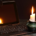 A candle alongside a computer during a power outage