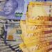 South African bank notes featuring images of former South African President Nelson Mandela (R) are displayed next to the American dollar notes in this photo illustration in Johannesburg.