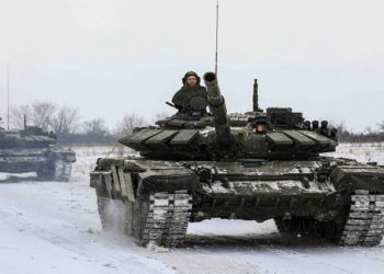 An army tank seen driving through snow.