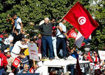 Demonstrators carry flags and banners during a protest against Tunisia's President.