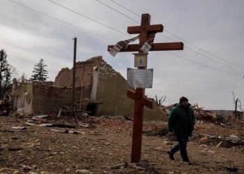 A man walks by the debris of a cultural center and an administration building that were destroyed during aerial bombing, in the village of Byshiv outside Kyiv, Ukraine, March 12, 2022.