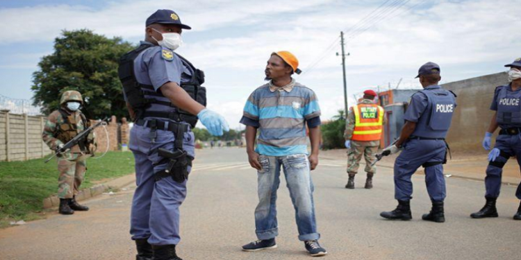 A member of the South African police on patrol stops a man during a nationwide lockdown for 21 days to try to contain the coronavirus disease (COVID-19) outbreak, in Eldorado Park, South Africa, March 30, 2020.