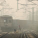 A woman crosses railway tracks as a goods train passes by on a smoggy day in New Delhi, India.