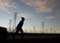 File image: A man pulls a trolley as he walks past electricity pylons in South Africa,