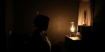 A woman looks on next to a paraffin light during an electricity blackout in Soweto, South Africa, March 18, 2021.