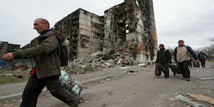 Local residents walk past a building destroyed during Ukraine-Russia conflict in the southern port city of Mariupol, Ukraine April 3, 2022.