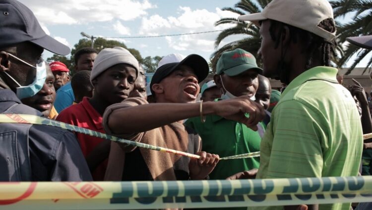 A group of people stand near a crime scene in Diepsloot.
