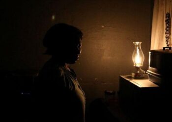 A women looks on next to a paraffin light during a blackout in Soweto, South Africa, March 18, 2021.