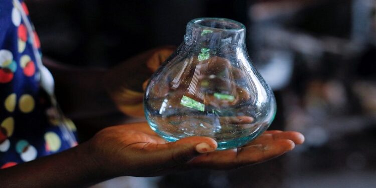 Glassblower Janet Offei, 28, holds a piece of glassware produced at Michael Tetteh's glassware manufacturing workshop in Krobo Odumase, Ghana March 18, 2022.