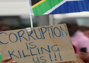 File image: A protester holds a placard during a march against corruption, gender-based violence and farm murders, in Cape Town.
