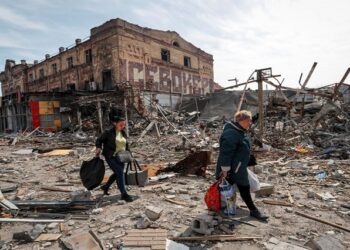 Residents carry their belongings near buildings destroyed in the course of Ukraine-Russia conflict, in the southern port city of Mariupol, Ukraine April 10, 2022.