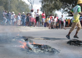 Diepsloot residents are seen in the background as tyres burn on the streets of the township located north of Johannesburg, where residents are protesting against rampant crime in the area