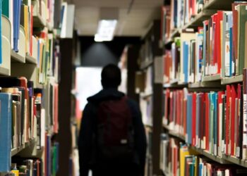 Student walks around a library aisle.