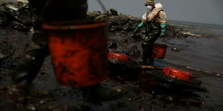 Workers clean up an oil spill following an underwater volcanic eruption in Tonga, in Ancon, Peru January 25, 2022.